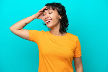 Arjantinli genç bir kadın mavi arka planda izole edilmiş, gülümsüyor.