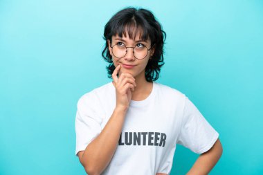 Young volunteer Argentinian woman isolated on blue background having doubts