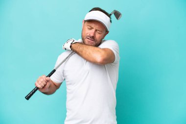 Orta yaşlı beyaz golfçü adam mavi arka planda izole edilmiş, omuz ağrısı çekiyor, çabaladığı için.