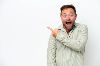Beyaz arka planda izole edilmiş orta yaşlı beyaz adam şaşırmış ve işaret ediyor.
