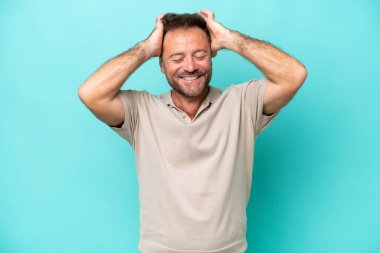 Orta yaşlı beyaz bir adam mavi arka planda izole edilmiş gülüyor.