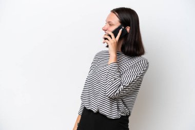 Beyaz arka planda izole edilmiş genç beyaz bir kadın cep telefonuyla sohbet ediyor.