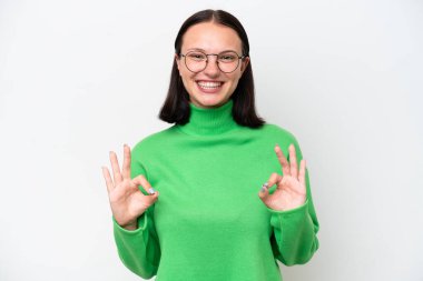 Beyaz arka planda izole edilmiş beyaz bir kadın iki eliyle tamam işareti gösteriyor.