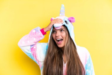 Sarı arka planda izole edilmiş tek boynuzlu at pijaması giyen beyaz bir kadın çok fazla gülümsüyor.