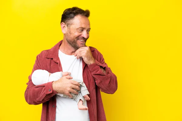 Middelbare Leeftijd Blanke Man Houdt Zijn Pasgeboren Zoon Geïsoleerd Gele — Stockfoto