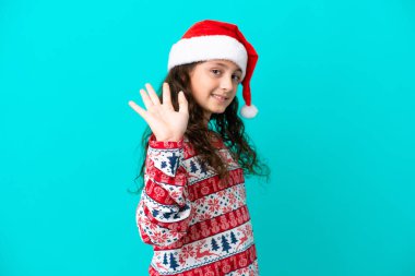 Mavi arka planda izole edilmiş küçük beyaz şapkalı mutlu bir ifadeyle selamlıyor.