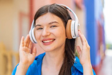 Açık havada müzik dinleyen genç ve güzel bir kadın.