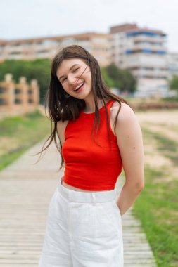 Genç, güzel bir kadın açık havada, mutlu bir ifadeyle.