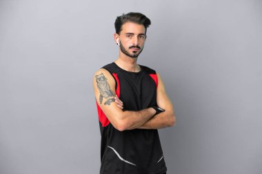 Gri arka planda izole edilmiş, kolları bağlı genç beyaz bir adam.