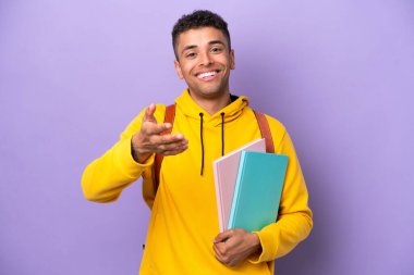 Mor arka planda izole edilmiş Brezilyalı genç bir adam iyi bir anlaşma için el sıkışıyor.