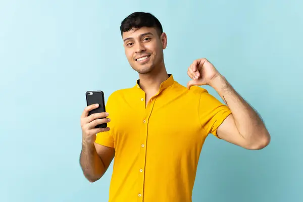 携帯電話を使用している若いコロンビアの男は 誇りと自己満足オムブルの背景を隔離しました — ストック写真