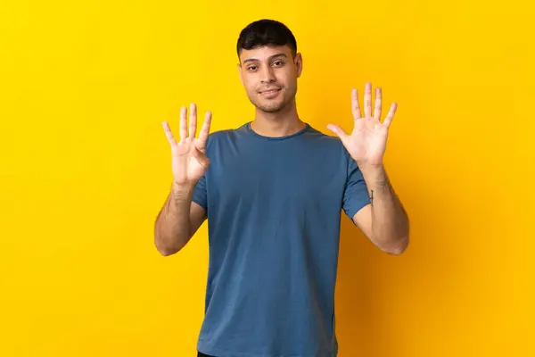 被黄色背景隔离的哥伦比亚年轻人用手指数着9 — 图库照片