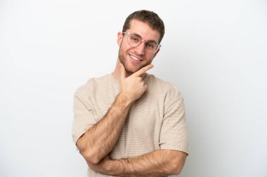 Beyaz arka planda izole edilmiş genç beyaz adam mutlu ve gülümsüyor.