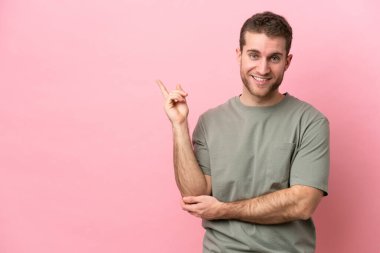 Pembe arka planda izole edilmiş genç, beyaz bir adam.