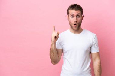 Pembe arka planda izole edilmiş genç beyaz adam çözümü bulmak için parmağını kaldırıyor.