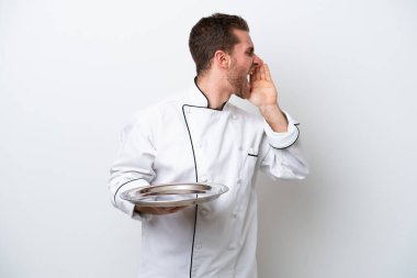 Beyaz arka planda izole edilmiş beyaz tepsisi olan beyaz tenli genç aşçı ağzı sonuna kadar açık bağırıyor.