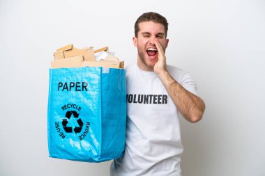 Beyaz arka planda izole edilmiş, ağzı açık bağırarak geri dönüşüm için kağıt dolu bir çanta tutan genç beyaz bir adam.