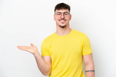 Beyaz arka planda izole edilmiş beyaz tenli yakışıklı bir adam, bir ilan vermek için avucunda hayali bir fotokopi makinesi tutuyor.