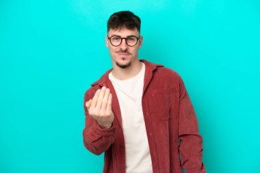 Beyaz tenli yakışıklı bir adam mavi arka planda izole edilmiş ve bizimle gelmesi için davet ediliyor. Gelmene sevindim.