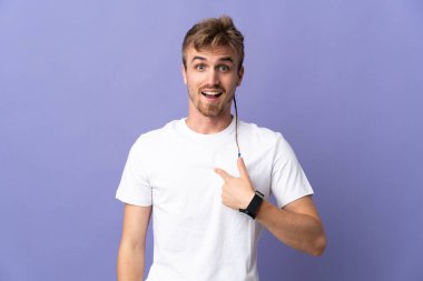 Mor arka planda yüzü sürpriz bir ifadeyle izole edilmiş yakışıklı sarışın bir adam.