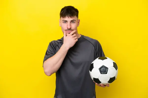 黄色いバックグラウンド思考で孤立した若いサッカー選手 — ストック写真