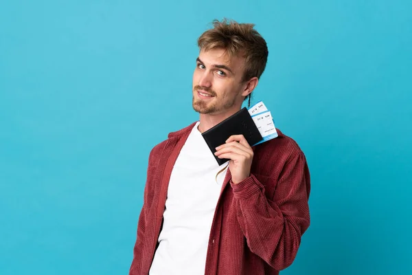 若いハンサムな金髪の男は パスポートと飛行機のチケットで休暇で幸せに青い背景で孤立しました — ストック写真