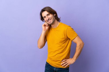 Mor arka planda yalnız, yakışıklı bir adam gülüyor.