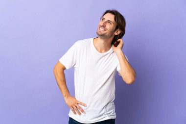 Mor arka planda izole edilmiş genç bir adam bir fikir düşünüyor.