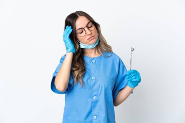 Romen kadın diş hekimi, pembe arka planda izole edilmiş baş ağrısıyla aletleri tutuyor