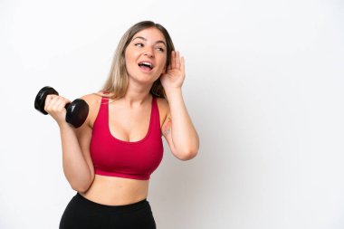 Genç Romen spor kadını halter kaldırıyor. Beyaz arka planda izole edilmiş bir şekilde. Kulağına elini koyarak bir şeyler dinliyor.