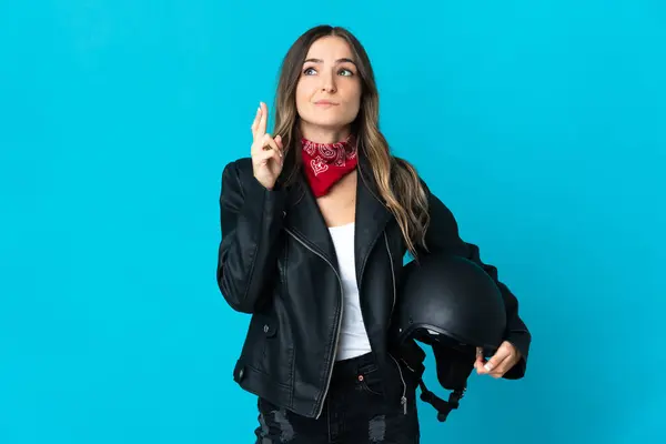 オートバイのヘルメットを保持しているルーマニアの女性は 指を交差して最善を望んで青い背景に隔離 — ストック写真
