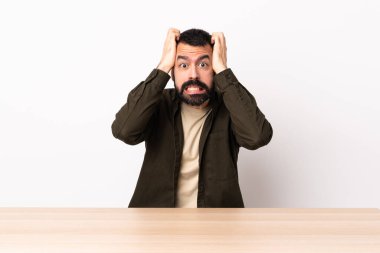 Masada sakallı beyaz bir adam gergin hareketler yapıyor..