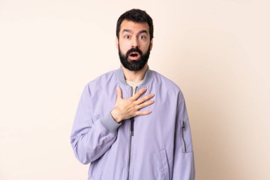 Sakallı, ceketli beyaz bir adam izole bir arka planda, sağa bakarken şaşırmış ve şok olmuştu.