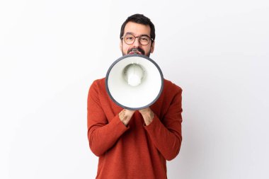 Sakallı, beyaz arka planda beyaz tenli, beyaz bir adam megafondan bağırıyor.