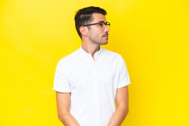Izole sarı arka plan üzerinde genç yakışıklı adam yan bakıyor