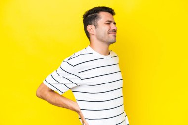 Bir çaba yapmış olduğu için sırt ağrısı muzdarip izole sarı arka plan üzerinde Genç yakışıklı adam