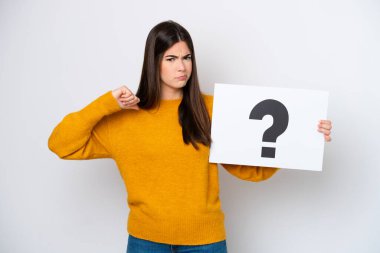 Beyaz arka planda izole edilmiş genç Brezilyalı bir kadın soru işareti olan bir levha tutuyor ve kötü sinyal veriyor.