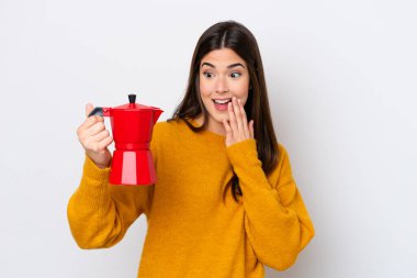 Elinde kahve makinesini tutan Brezilyalı genç bir kadın beyaz arka planda izole edilmiş, şaşırmış ve şok olmuş bir yüz ifadesi var.