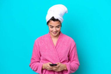 Mavi arka planda bornozu olan genç Brezilyalı kadın cep telefonuyla mesaj yolluyor.