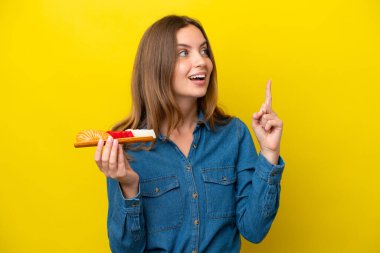 Sarı arka planda saşimi tutan Kafkasyalı genç bir kadın parmağını kaldırarak çözümü bulmaya çalışıyor.