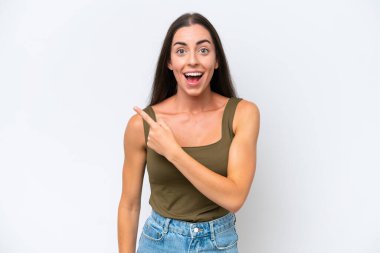 Beyaz arka planda izole edilmiş genç beyaz kadın şaşırmış ve işaret ediyor.
