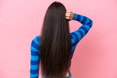 Genç beyaz kadın pembe arka planda izole edilmiş ve düşünüyor.