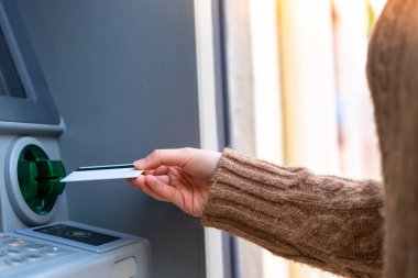 Açık havada kredi kartı tutan genç bir kadın.