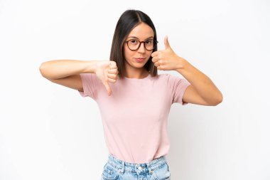 Beyaz arka planda izole edilmiş beyaz bir kadın iyiye-kötüye işaret yapıyor. Evet ya da hayır arasında kararsız