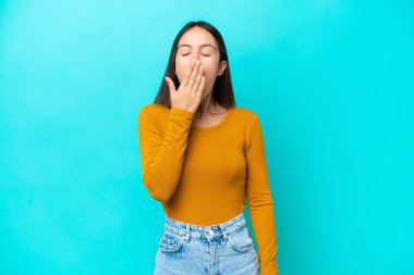 Kafkasyalı genç bir kadın mavi arka planda izole edilmiş telefon jestleri yapıyor.