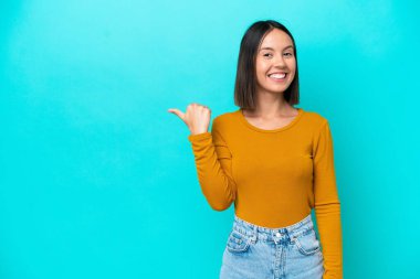 Kafkasyalı genç kadın mavi arka planda izole edildi. Çözümün farkına varmak için parmağını kaldırdı.