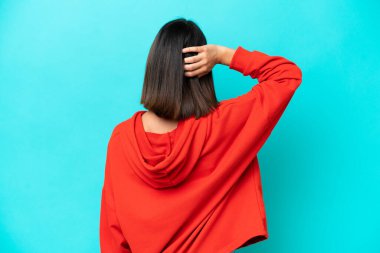 Mavi arka planda izole edilmiş genç beyaz kadın gülüyor.