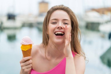 Kornet dondurması olan genç kızıl saçlı kadın ağzı açık bağırıyor.