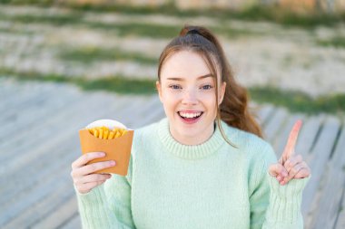 Dışarıda patates kızartması tutan güzel bir kız harika bir fikri işaret ediyor.