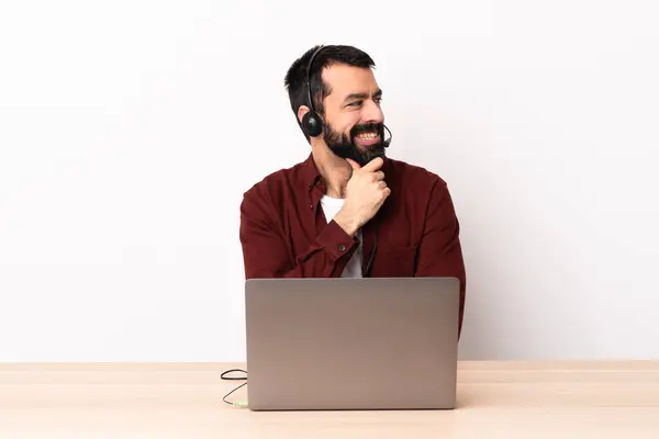ヘッドセットとノートパソコンで仕事をしているテレマーケティング担当者の白人男性は横を向いて笑っています — ストック写真